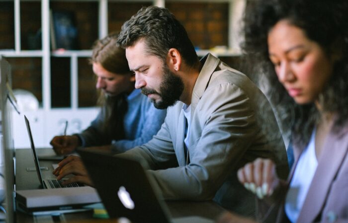 a group of people in a social services office sitting at a table with laptops