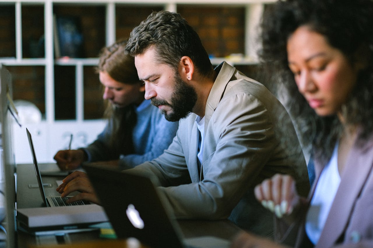 a group of people in a social services office sitting at a table with laptops